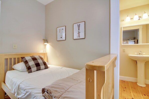 A bedroom with a wooden bed, a white wall, and a wooden radiator. - All-season Ludlow Apartment: 3 Mi to Okemo Resort! (Ludlow)