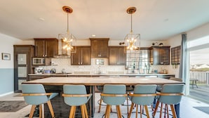 Una cocina moderna con una isla grande, taburetes de bar e iluminación colgante.