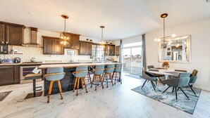 Una cocina moderna con una isla grande, taburetes de bar e iluminación colgante.