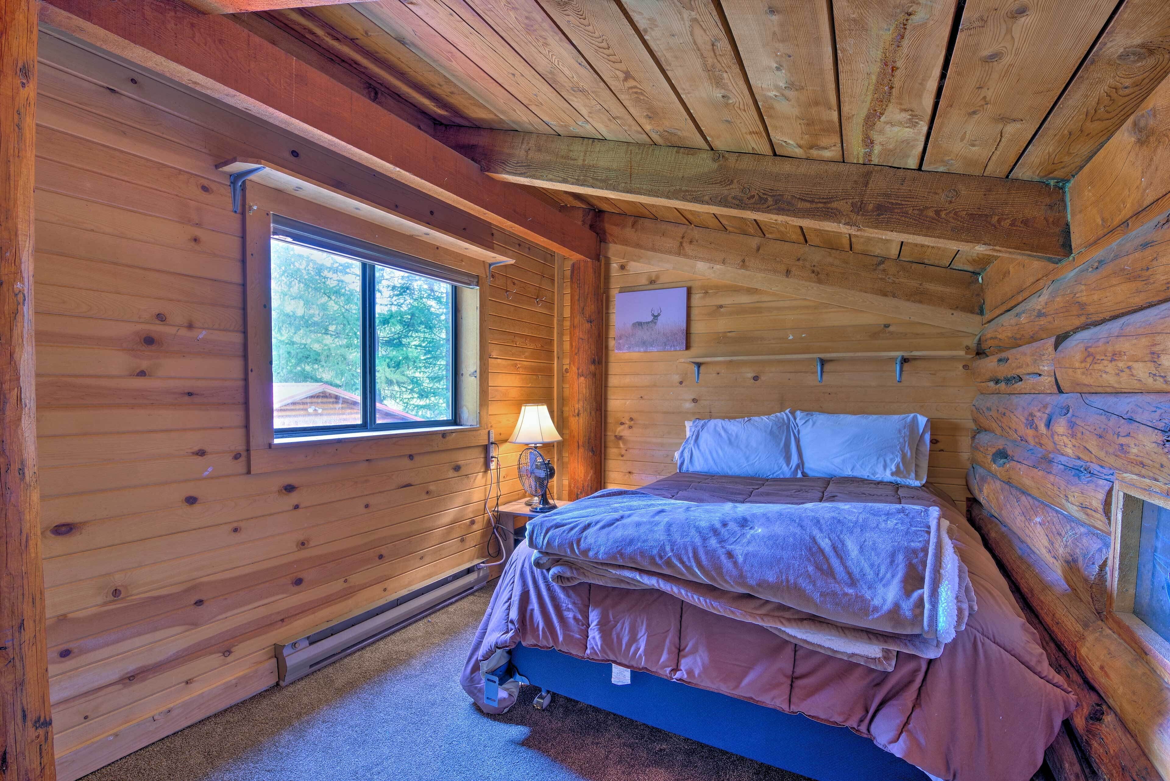 A cozy cabin room with a bed, a window, and a picture on the wall.