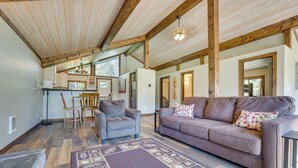 A spacious living area with a wooden ceiling, a sofa, a coffee table, and a rug. - Donnelly Cabin w/ Fire Pit: 5 Mi to Boat & Ski! (Donnelly)