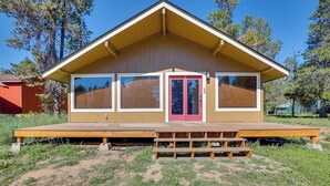 A single-story building with a flat roof, a front porch with a bench, and a red door. - Donnelly Cabin w/ Fire Pit: 5 Mi to Boat & Ski! (Donnelly)