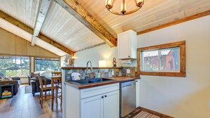 A kitchen with wooden cabinets, a sink, and a window overlooking a wooded area. - Donnelly Cabin w/ Fire Pit: 5 Mi to Boat & Ski! (Donnelly)