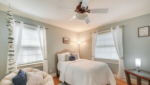 A bedroom with a bed, a chair, a bedside table, a ceiling fan, and a wall with a framed quote. - Quaint Goldsboro Home w/ Screened-in Porch! (Goldsboro)