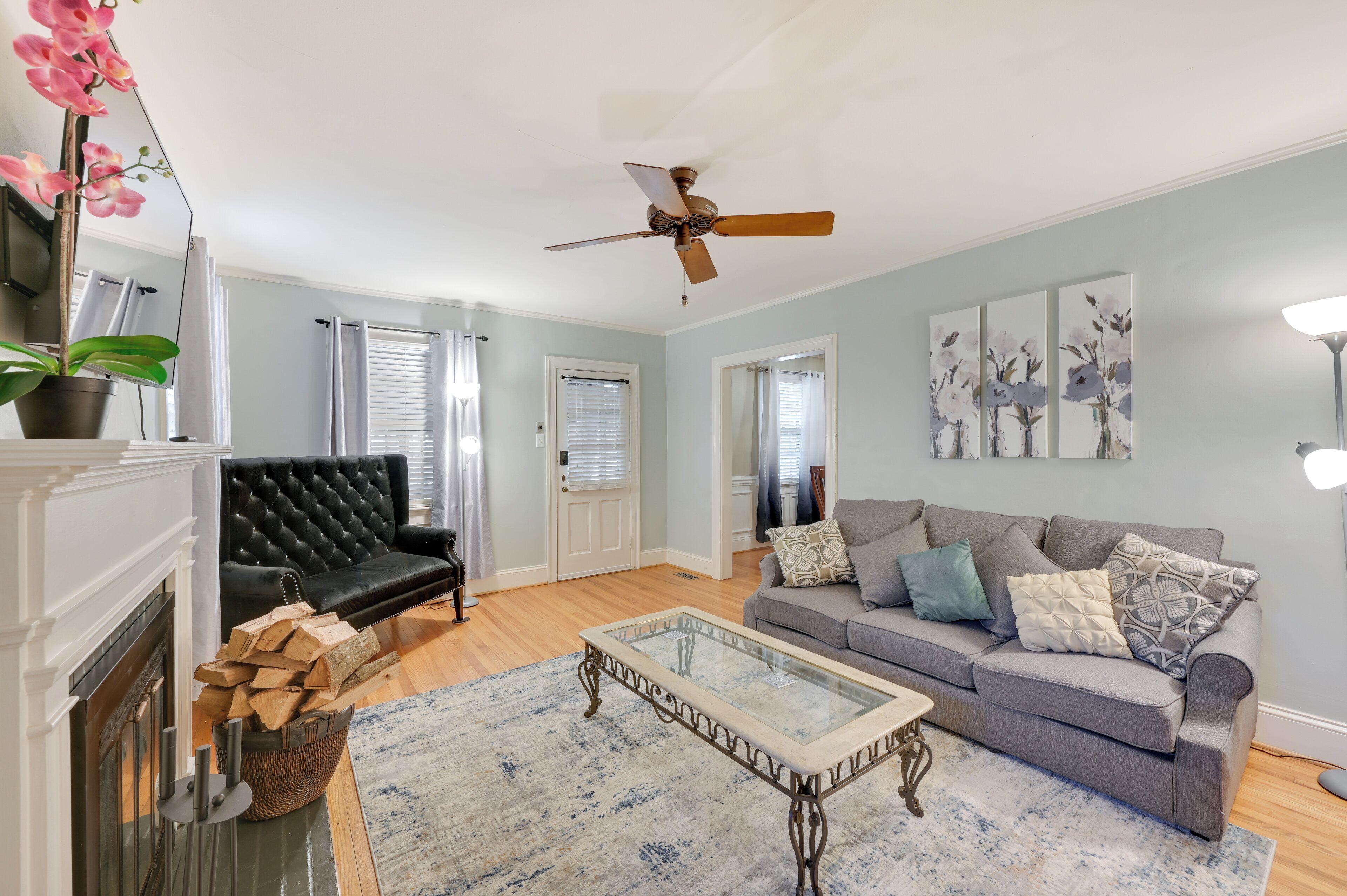 A living room with a fireplace, a ceiling fan, a grey sofa, and a coffee table.