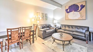 A living room with a sofa, chairs, a coffee table, and a painting on the wall.