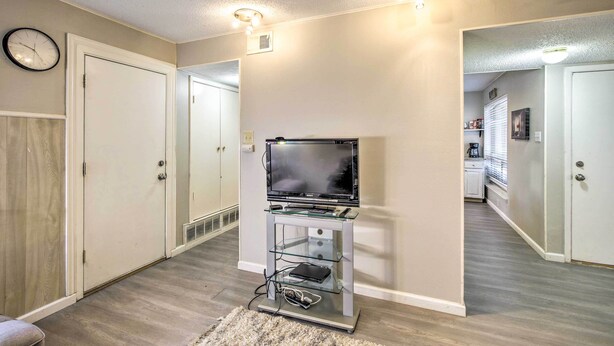 A hallway with a TV on a stand, a clock, and a door.
