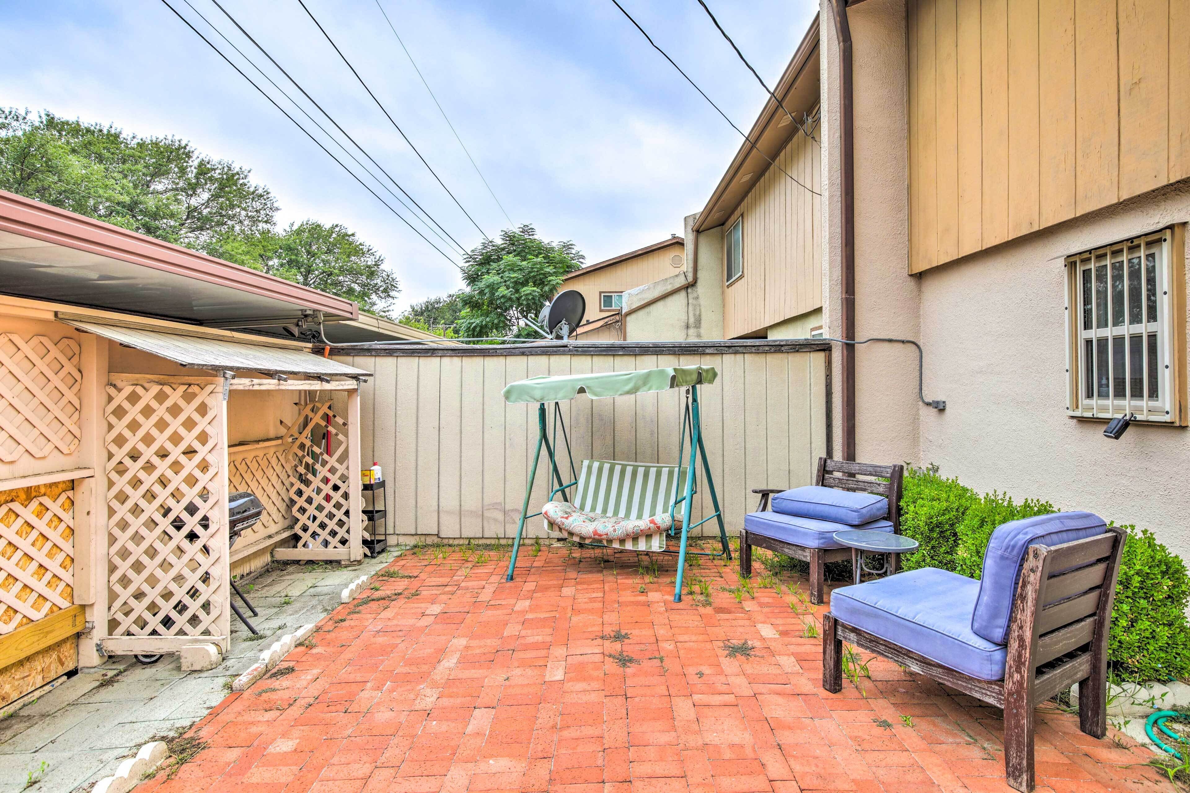 Une terrasse avec une balançoire, une chaise en bois et une petite table.