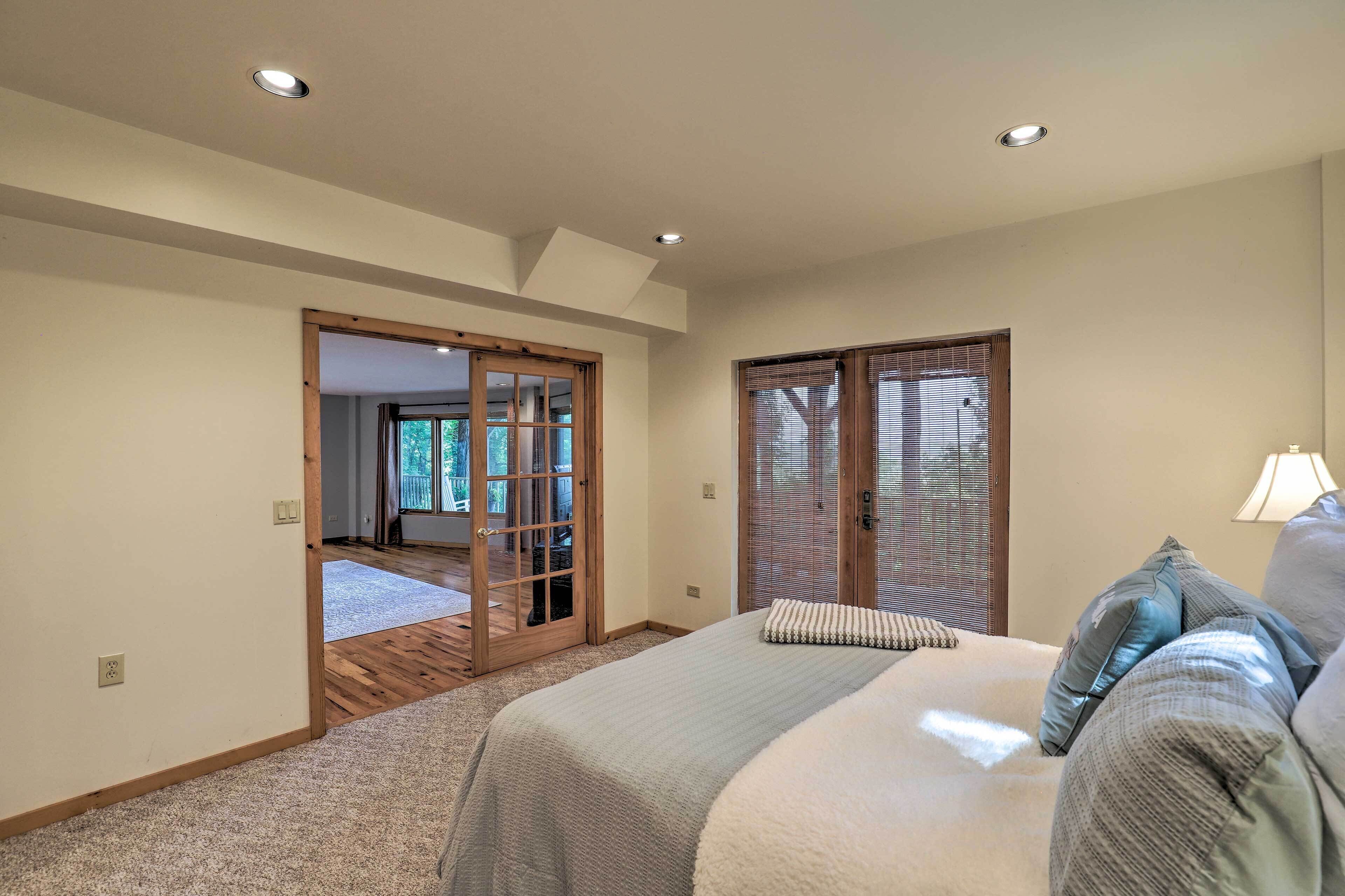Un dormitorio con una cama grande, una puerta de madera que da a un balcón y una ventana con persianas.