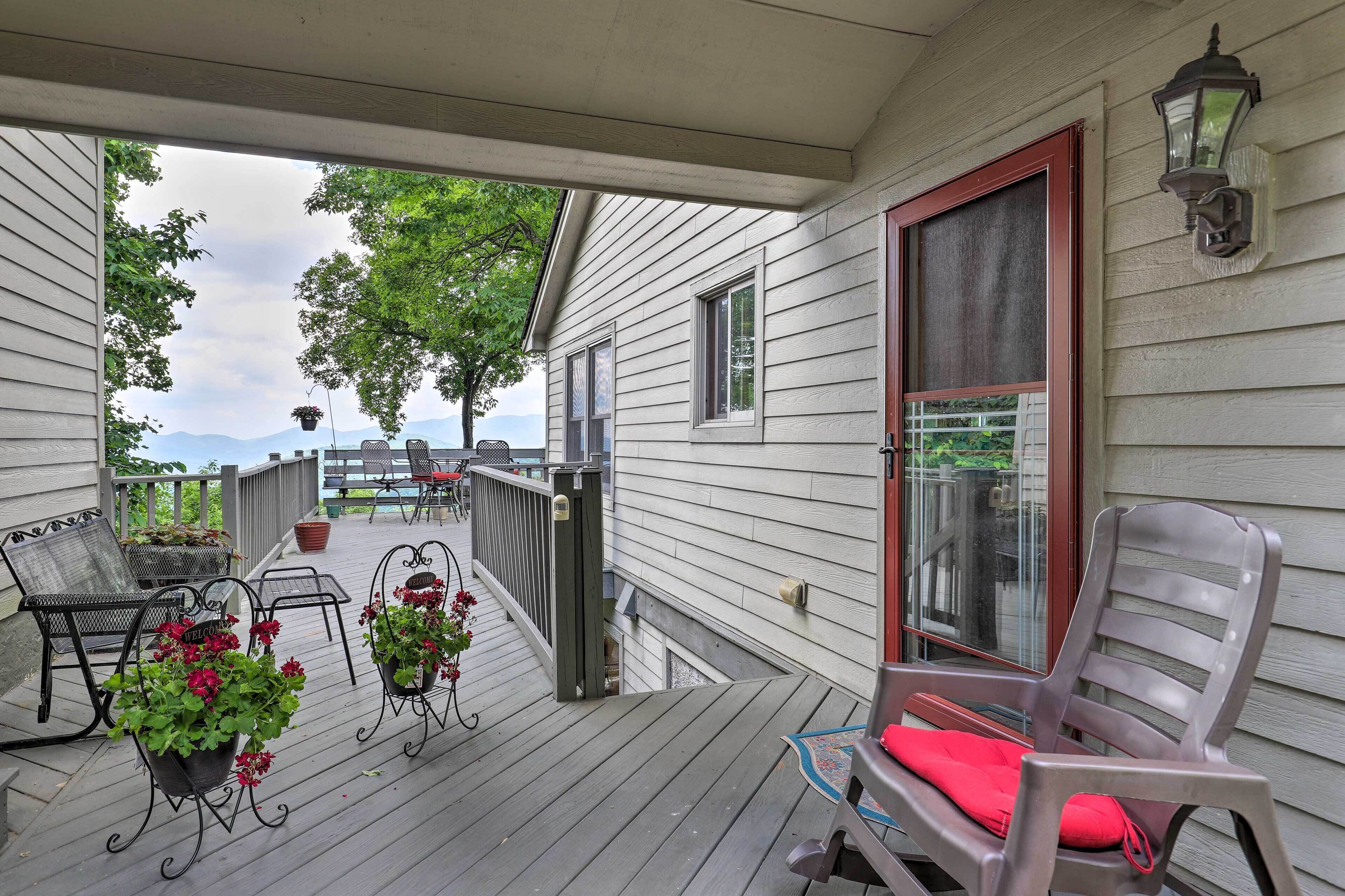 A covered porch with outdoor furniture, potted plants, and a view of the mountains.