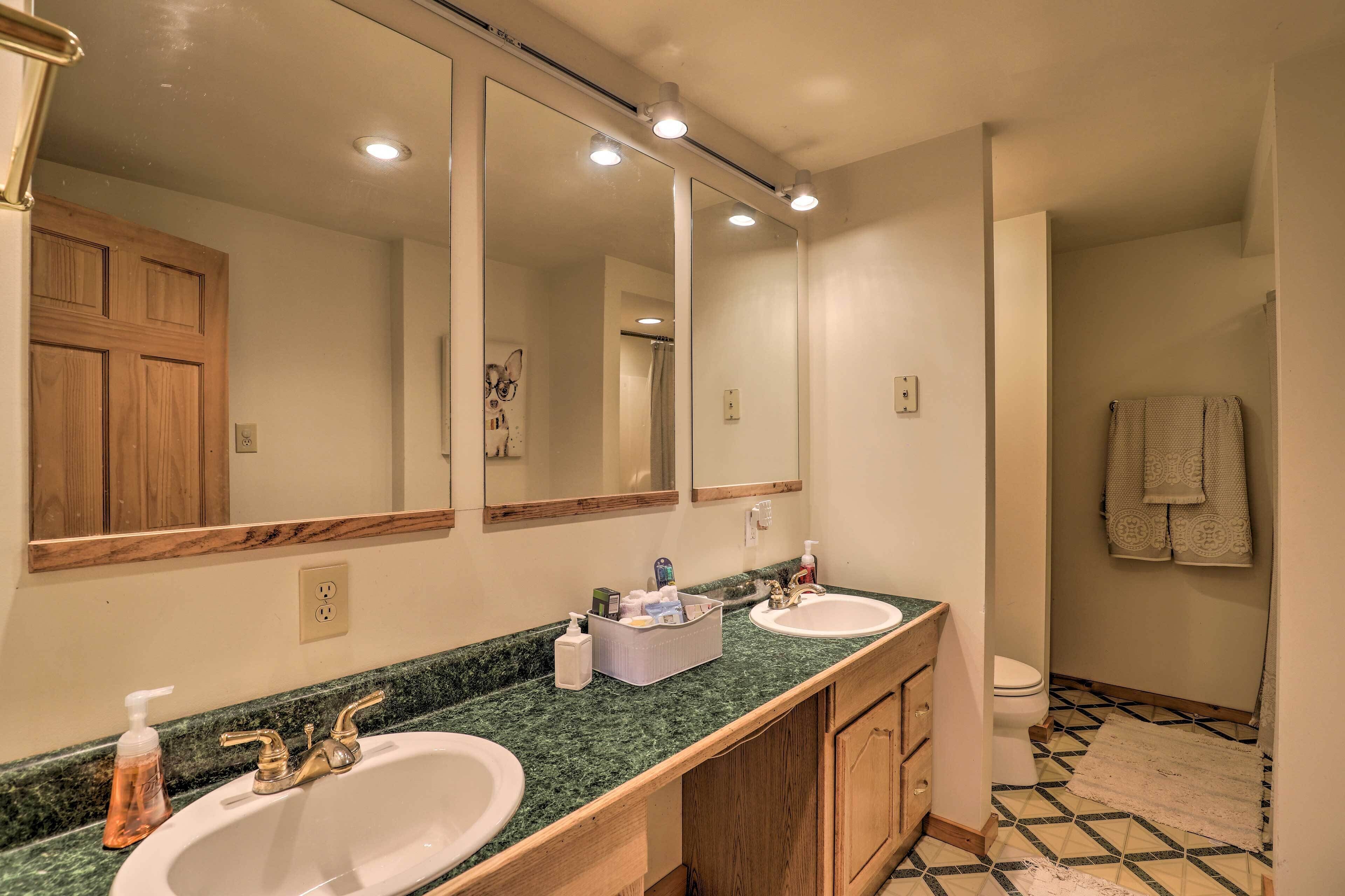 A bathroom with two sinks, a large mirror, and a shower.