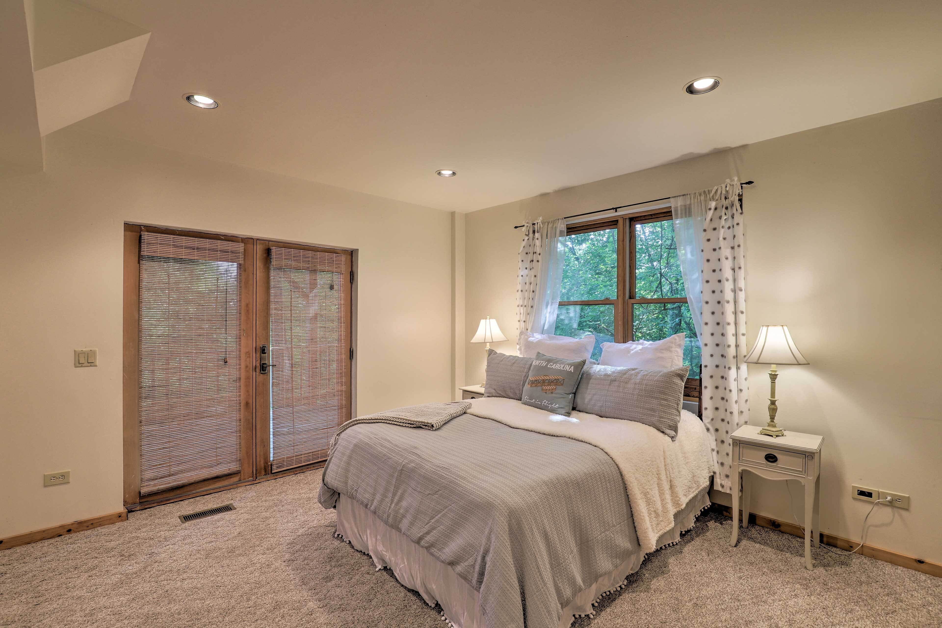 Une chambre à coucher comprenant un lit, une table de chevet, une fenêtre avec des rideaux et une porte coulissante.