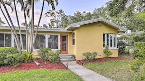 A yellow house with a red door, a front porch, and a small garden with red mulch and green grass. - Florida Home ~ 10 Mi to St Pete Beach! (St. Petersburg)