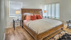 A bedroom with a wooden bed, two bedside tables with lamps, and a large window with blinds. - Florida Home ~ 10 Mi to St Pete Beach! (St. Petersburg)