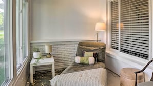 A cozy room with a bed, a small table with a lamp, a potted plant, and a window with blinds. - Florida Home ~ 10 Mi to St Pete Beach! (St. Petersburg)