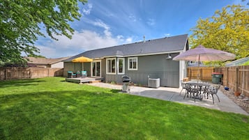Enjoy a peaceful retreat in this serene backyard with a patio, grill, and comfortable seating area.