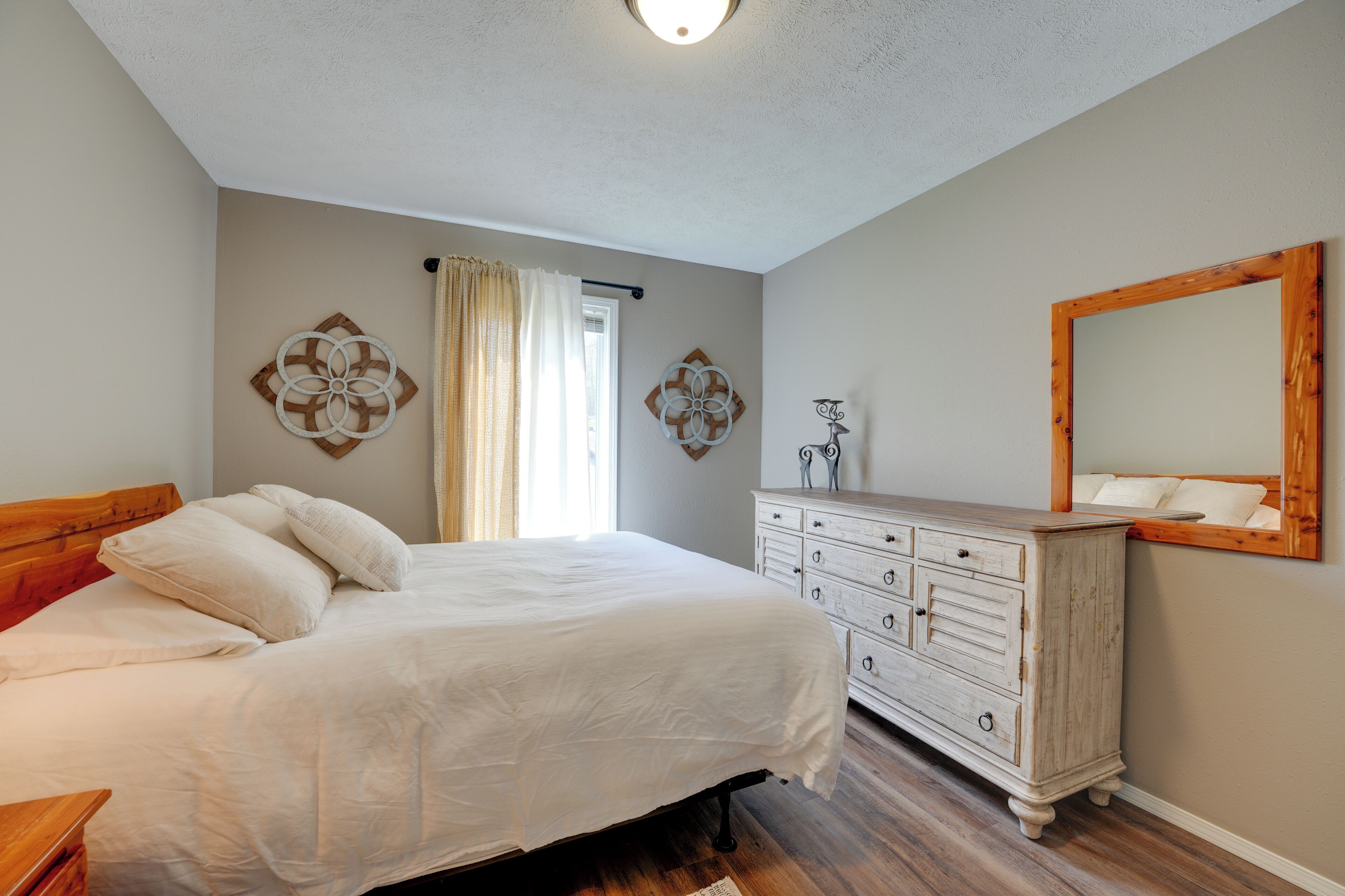 Un dormitorio con cama, cómoda y espejo en la pared.