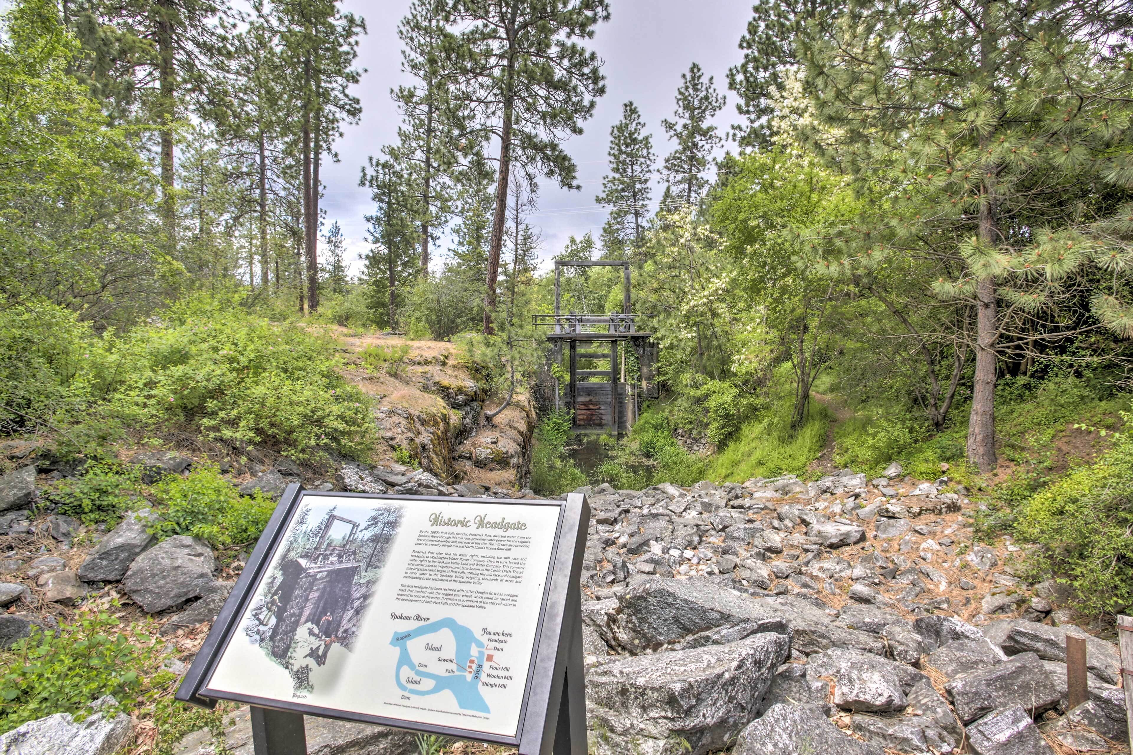 A historic headgate in a forested area with a signboard in the foreground.