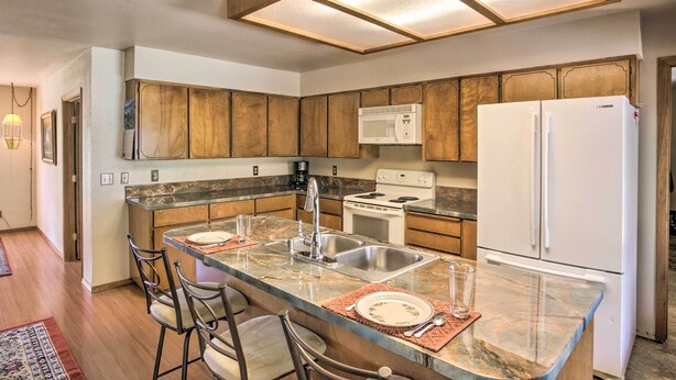 A kitchen with wooden cabinets, a central island with bar stools, a microwave, stove, and refrigerator.