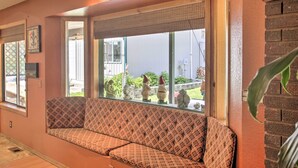A cozy room with a patterned sofa, a window with decorative items, and a brick wall.