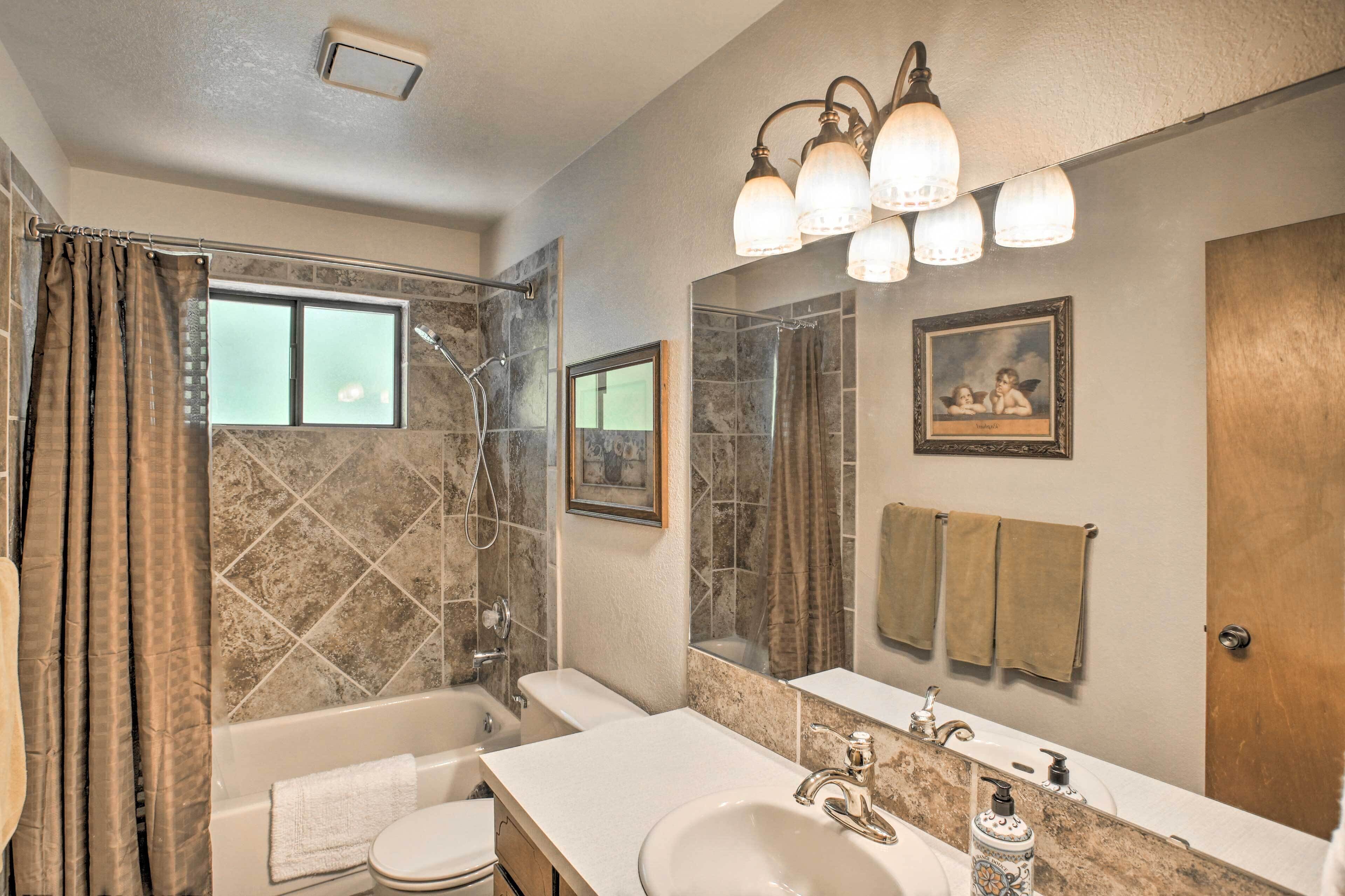 A bathroom with a bathtub, a shower, a toilet, a sink, and a vanity mirror.