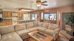 A living room with a beige sectional sofa, a glass-top coffee table, a ceiling fan, and a fireplace.