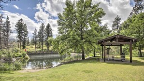 A park with a wooden pavilion, a pond, and surrounding trees.