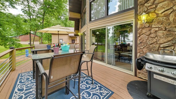 An outdoor deck with a table and chairs, a grill, and a stone wall. - Cozy Dover Home w/ Boat Dock, Fire Pit & Deck! (Dover)