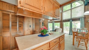 A kitchen with wooden cabinets, a central island, and a dining area with a table and chairs. - Cozy Dover Home w/ Boat Dock, Fire Pit & Deck! (Dover)