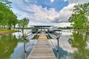 A wooden pier leading to a covered dock area with a lake in the background. - Cozy Dover Home w/ Boat Dock, Fire Pit & Deck! (Dover)