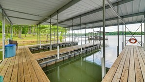 A covered dock area with wooden walkways over water, metal railings, and a lifebuoy. - Cozy Dover Home w/ Boat Dock, Fire Pit & Deck! (Dover)