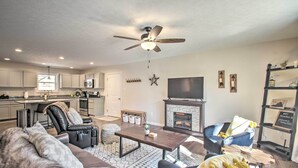 A modern living room with a fireplace, leather furniture, and a ceiling fan.