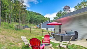 A backyard with a hot tub, outdoor seating, and a fire pit.