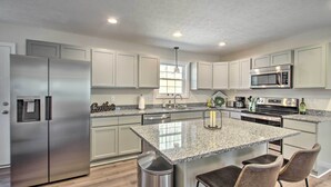 A modern kitchen with granite countertops, stainless steel appliances, and a central island with bar stools.