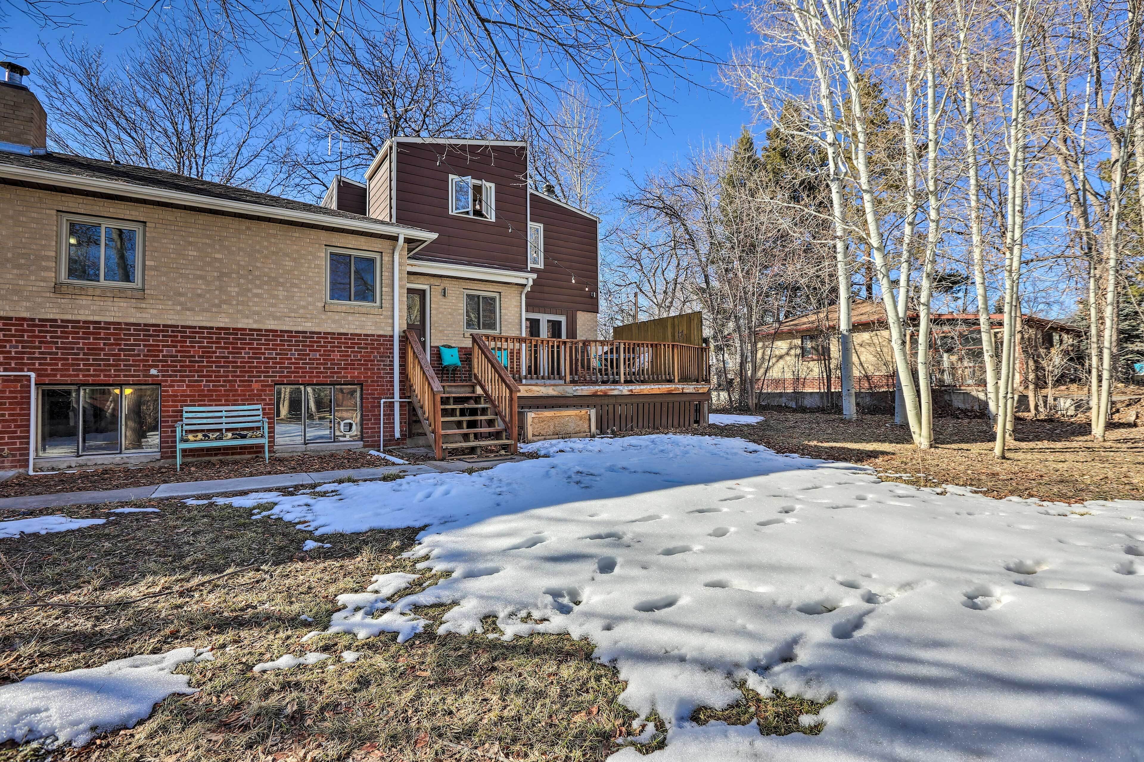 A two-story house with a deck, a front porch, and a snow-covered yard.
