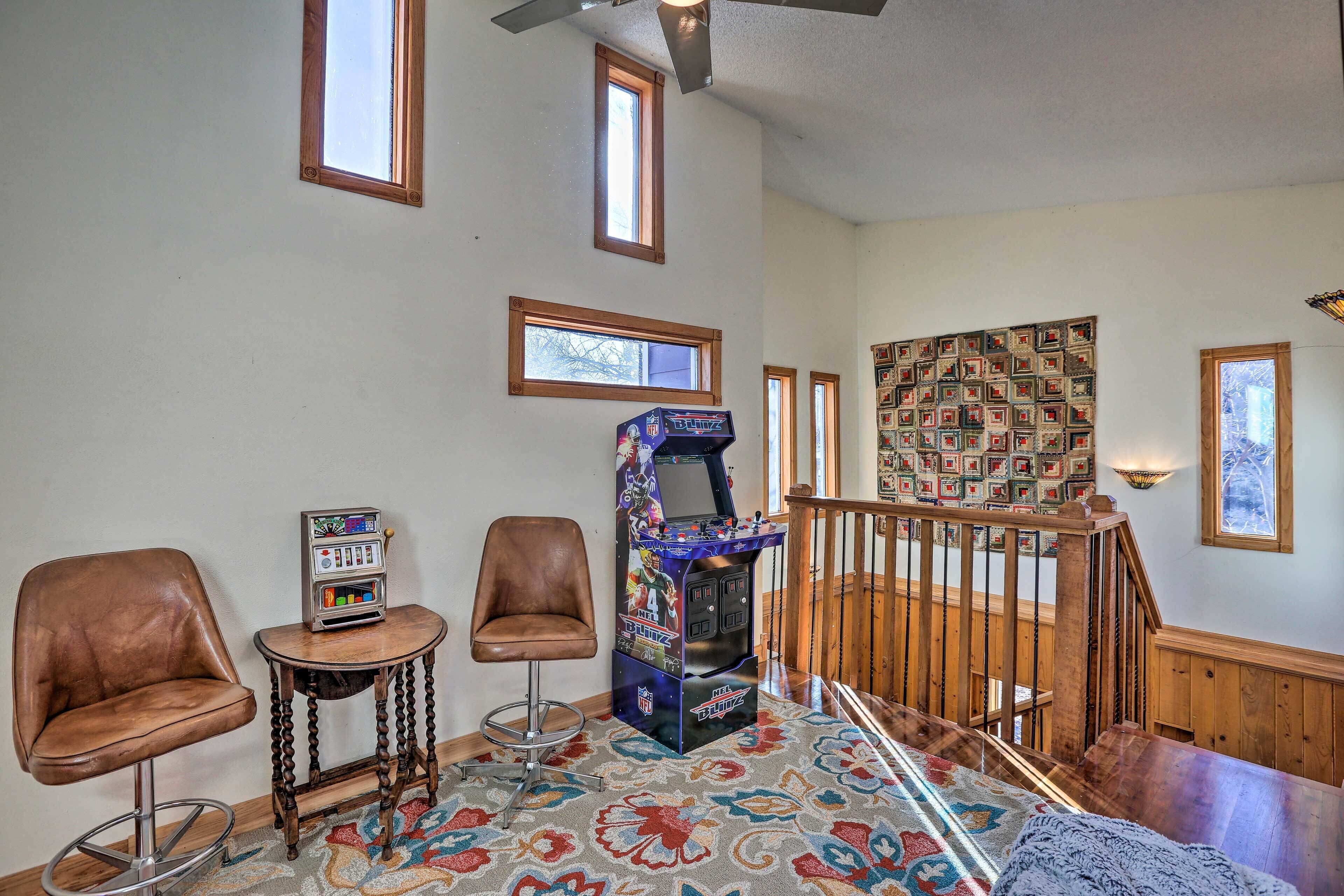 Une pièce comprenant un tabouret de bar, une petite table avec un juke-box, un tapis à motifs et un escalier avec une rampe en bois.