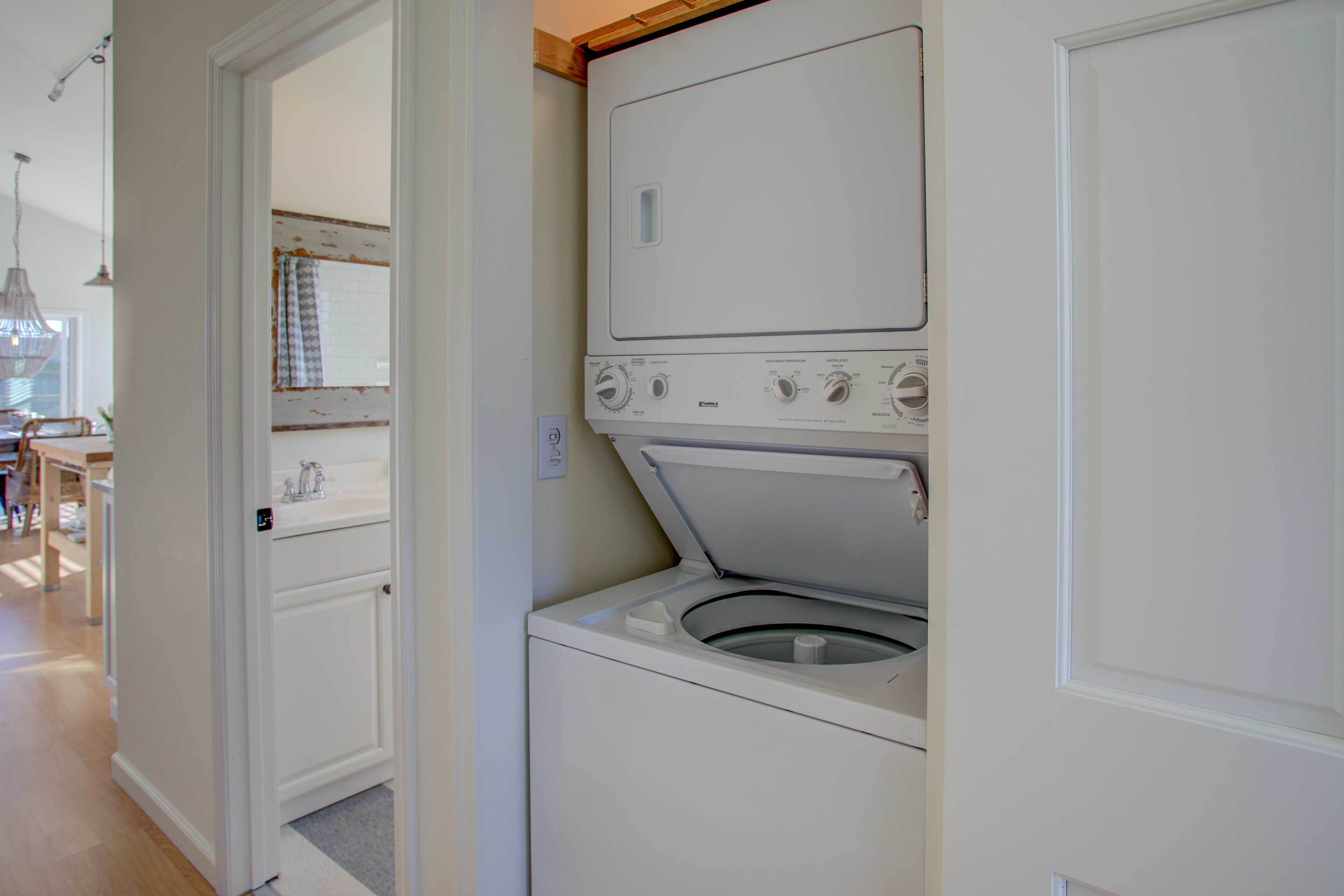 A laundry room with a washing machine and dryer, a sink, and a mirror.