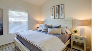A bedroom with a bed, bedside tables, a window with blinds, and wall art. - Walk to Ocean! Chic 'summer House Cottage' (Pacific Beach)