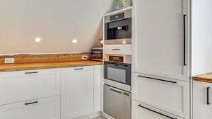 A kitchen with white cabinets, a wooden countertop, a built-in oven, a microwave, and a dishwasher. - Steps to NYC Train! Charming Carriage House Loft (Glen Ridge)