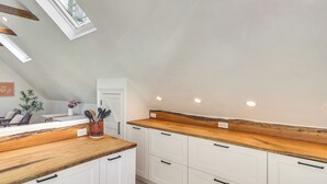 A modern kitchen with white cabinets, wooden countertops, and recessed ceiling lights. - Steps to NYC Train! Charming Carriage House Loft (Glen Ridge)