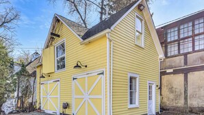 A yellow building with two garage doors and a small window. - Steps to NYC Train! Charming Carriage House Loft (Glen Ridge)