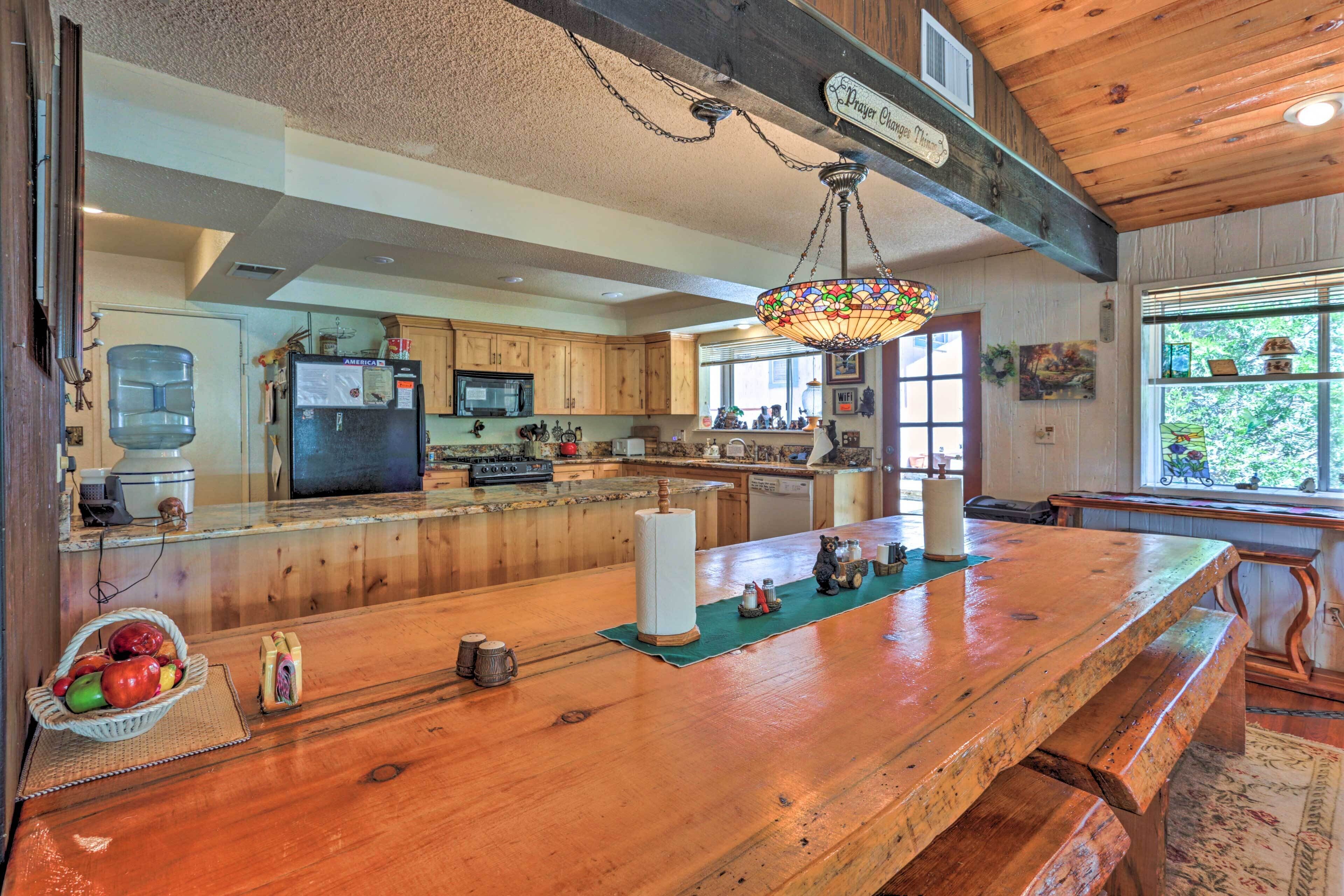 A spacious kitchen with wooden cabinets, a large island with a sink, and a hanging stained glass light fixture.