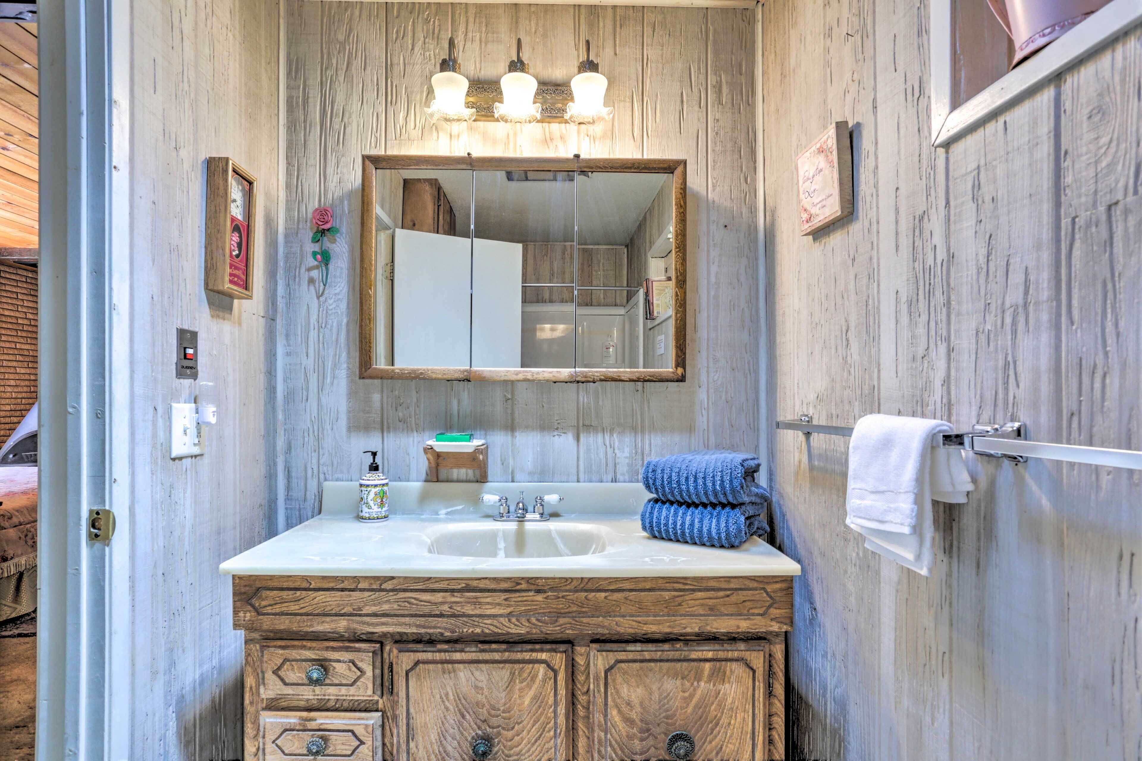 A rustic bathroom with a wooden vanity, a large mirror, and a towel rack.