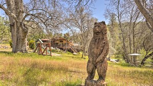 A bear statue in a natural setting with trees and a building in the background. - Gorgeous Oakhurst Retreat w/ Swimming Hole! (Oakhurst)