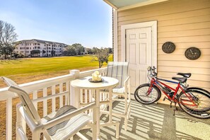 A porch with a white chair, a small table with a candle, and a red bicycle. - Resort Condo w/ Balcony & Pool Access! (North Myrtle Beach)