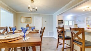 A dining area with a wooden table set for six, blue glassware, and a chandelier. - Charming Gulfport Home ~ 2 Mi to Marina (Gulfport)