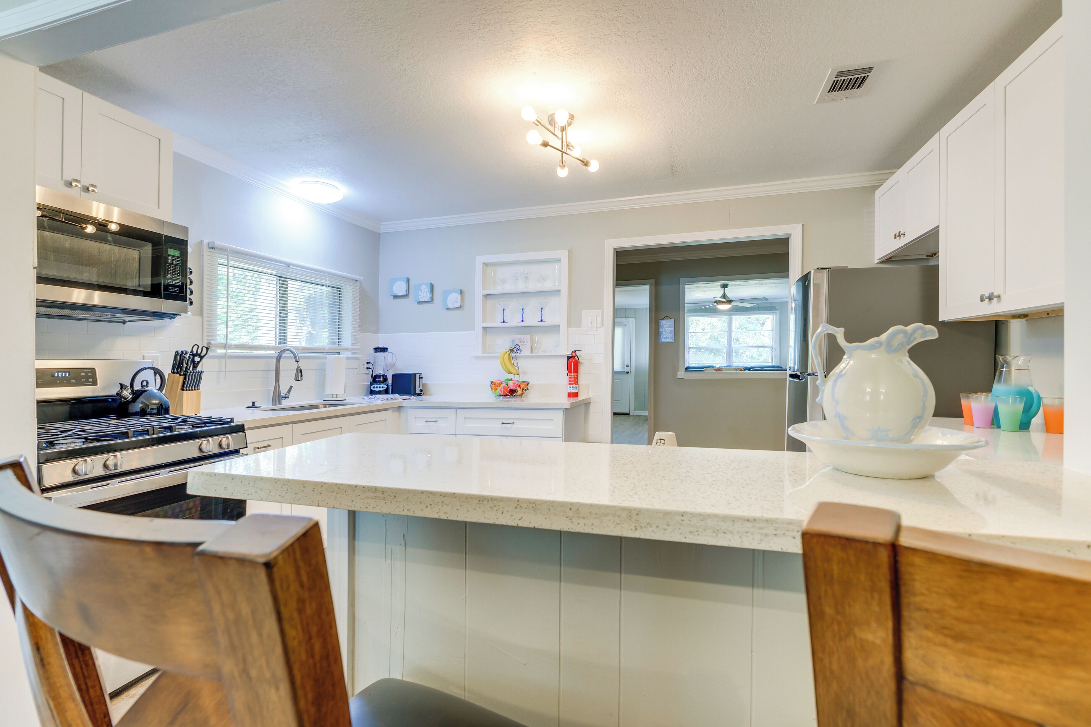Una cocina moderna con armarios blancos, una isla central, microondas, estufa y refrigerador.