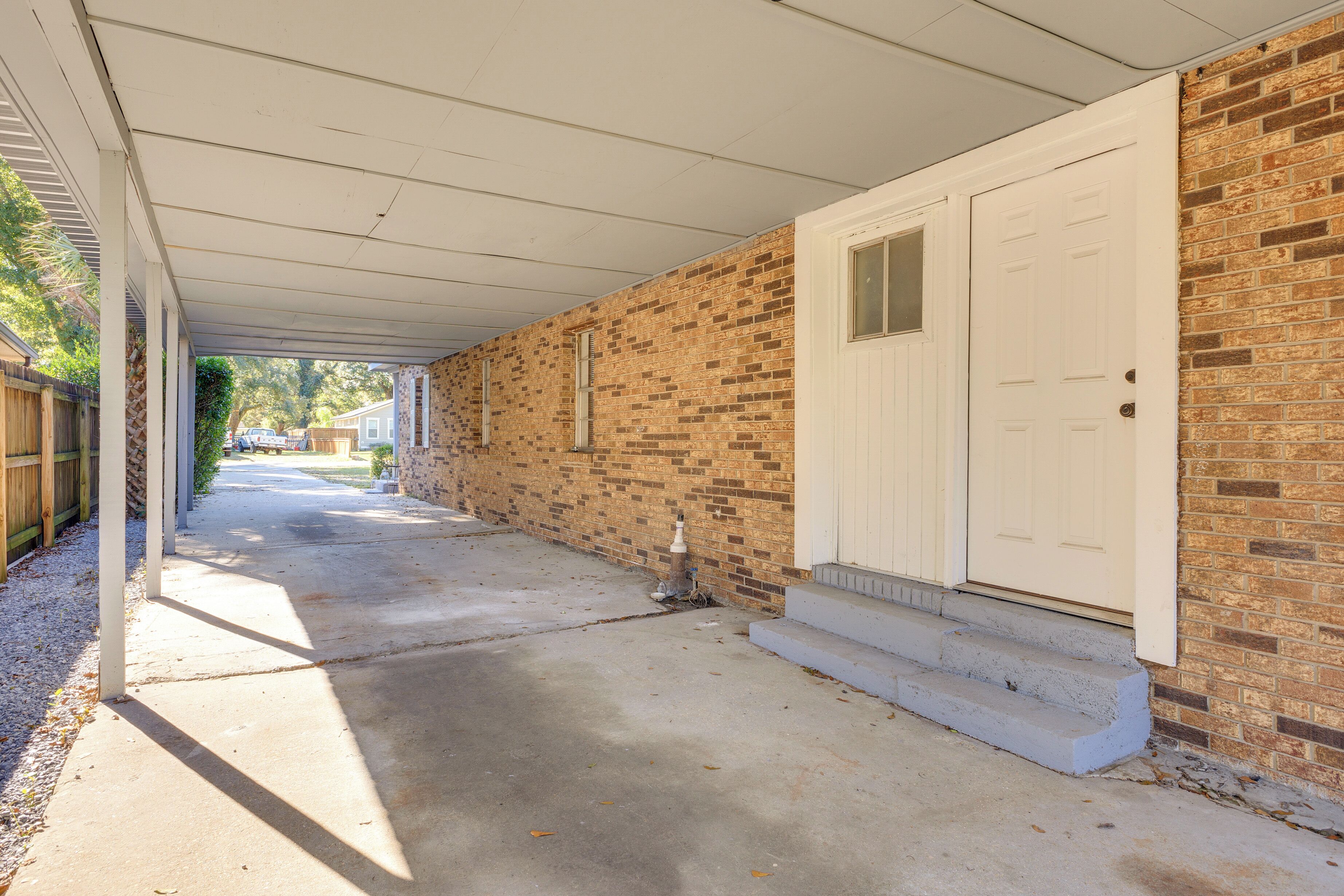 A covered porch with a brick wall and a white door.
