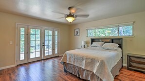 Ein Schlafzimmer mit Bett, Deckenventilator, Fenster und Tür.