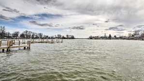 Un lac paisible, avec des quais en bois qui s’avancent dans l’eau, entouré d’arbres et de bâtiments en arrière-plan.